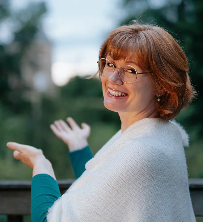 Frau mit Buch schaut aus einem Fenster